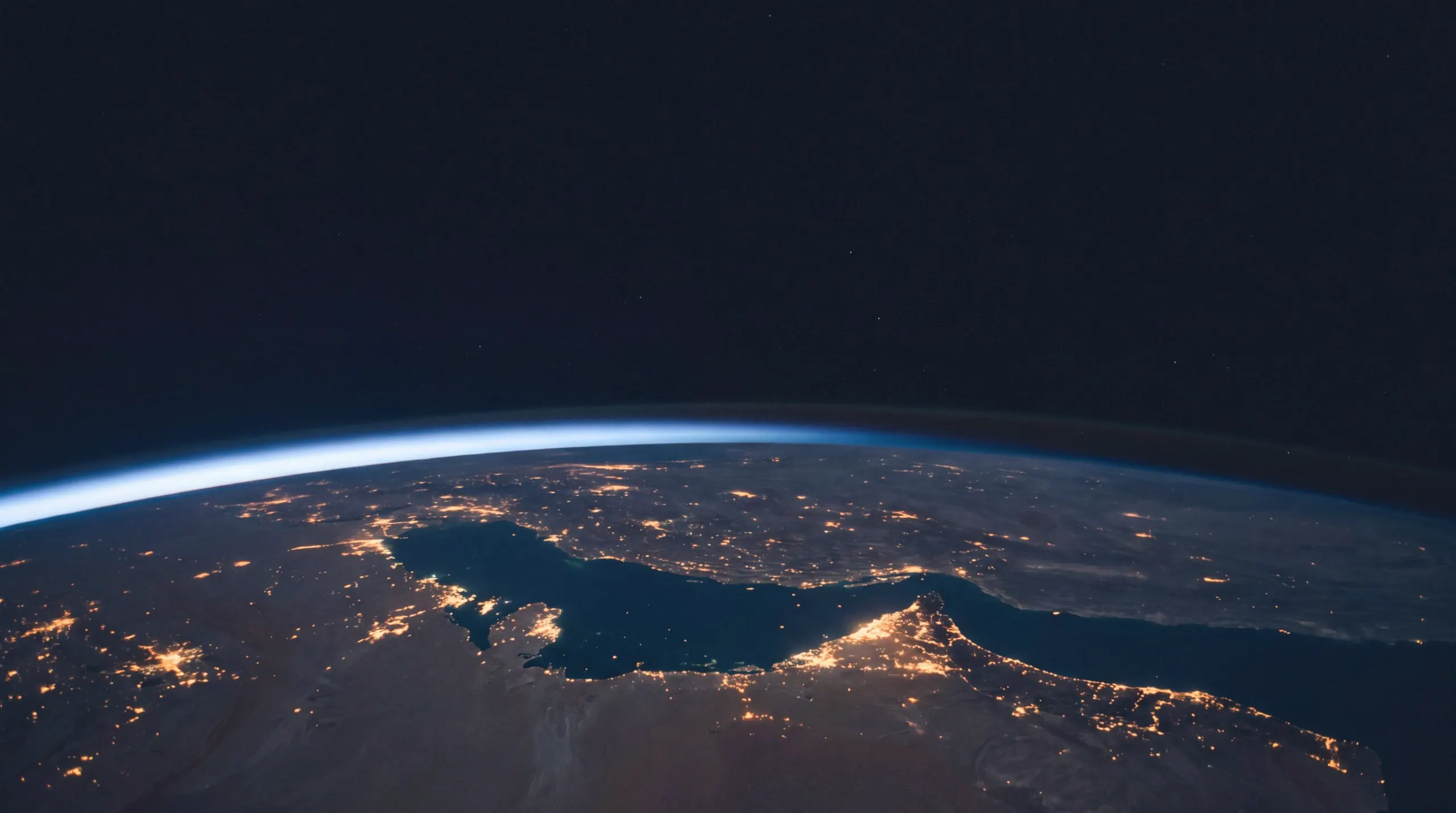 The night side of the Earth from the edge of space, with city lights along the Gulf coast and the glow of the atmosphere